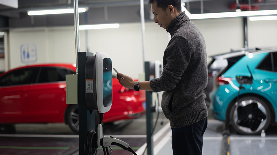 A man seeing his phone next to a charger in a parking lot