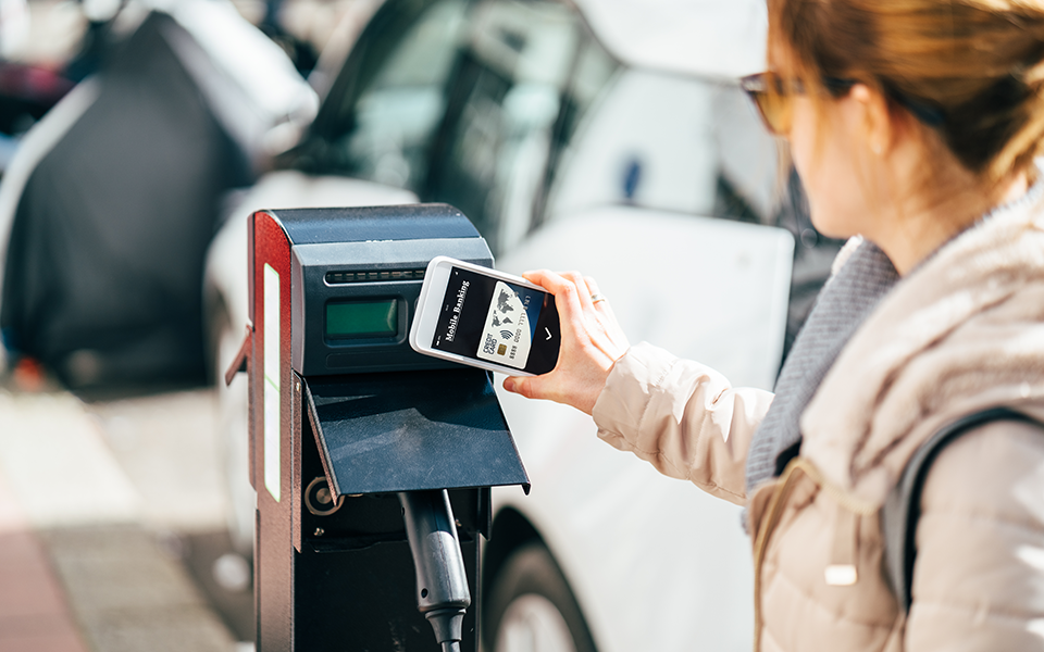 A woman using mobile screen to scan a code on an EV charger display