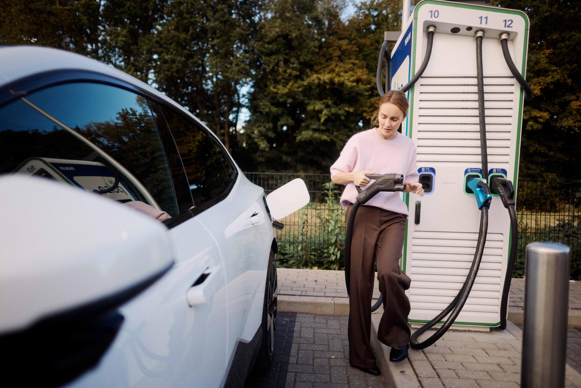 Female driver charging her EV at a charge point operator (CPO) public charge point